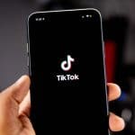 telefono in mano con schermata di avvio di TikTok