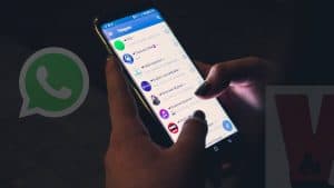 persona che sta guardando le chat su Telegram stanza buia icona WhatsApp in dissolvenza
