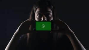 ragazza che esprime stupore con cellulare e schermata WhatsApp