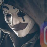 uomo con cappuccio e maschera davanti PC phishing Instagram
