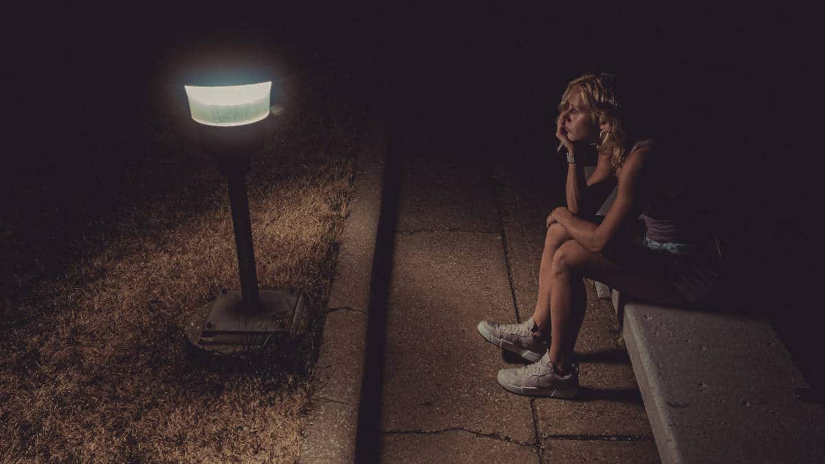 farsi lasciare ragazza seduta sul marciapiede che guarda un lampione